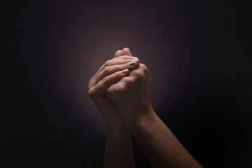 Praying hands with faith in religion and belief in God over dark background