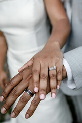 Newlywed couple Bride and African American groom in grey suit showing their wedding rings on hands Black wedding ring and white diamond ring Just married young couple showing up their rings 