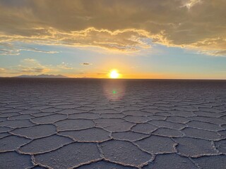 Pan view of dry ground with hexagonal salt formations on surface of Salar de Uyuni at sunrise, Bolivia
