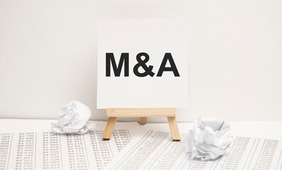 text m and a on easel with office tools and paper.Top view. Business concept