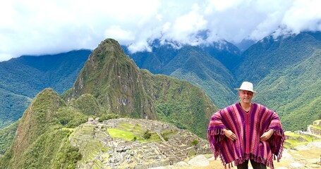 Scenic panoramic view behind a tourist in traditional peruvian clothing standing on Machu Picchu,...
