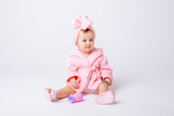 Cute little baby girl in pink terry with makeup isolated on a white background, repeats the behavior of mom