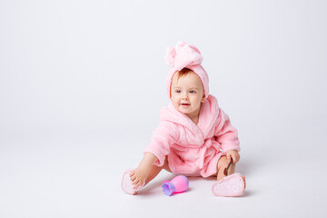 Cute little baby girl in pink terry with makeup isolated on a white background, repeats the behavior of mom