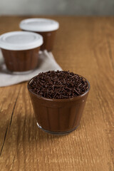 Fototapeta na wymiar Brazillian chocolate sweet called Brigadeiro in pot on wooden desk background. Vegan version