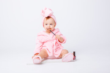 Cute little baby girl in pink terry with makeup isolated on a white background, repeats the behavior of mom