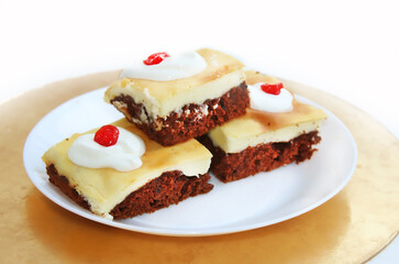 Cheesecake with chocolate biscuit. Pieces of cake on a white plate, sprinkled with sour cream and decorated with dried cherries