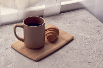coffee mug and croissant on cutting board