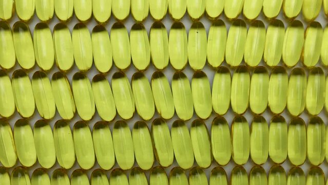 lots of yellow omega 3 oil pills lined up in rows and columns, healthy supplementation
