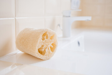 Natural loofah washcloth on the washbasin in the bathroom. Beauty, spa and wellness concept, copy...
