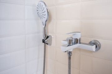 Faucet for hot and cold water, with a shower hose, mounted in a wall  in the bathroom. a modern...