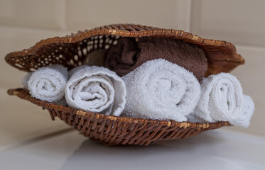 Terry white and brown towels in a wicker basket/  Beauty, spa and wellness concept, copy space