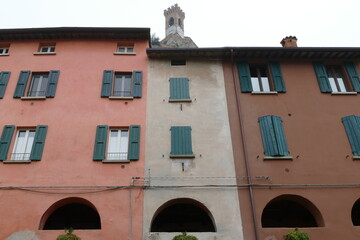 Colorful buildings in Brisighella with the arched windows of the elevated “donkey road” and the clock tower on the top of the hill in the background