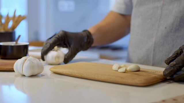 Male hands cutting garlic on a wooden board.