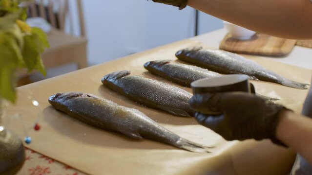 Man&rsquo;s hands pepper raw fish on the table