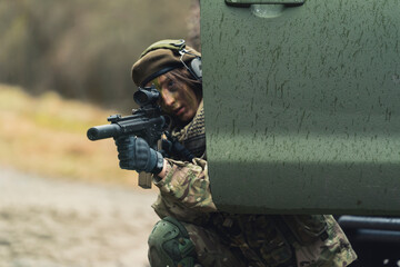 Cunning lady soldier hiding behind patrol truck door for cover. High quality photo