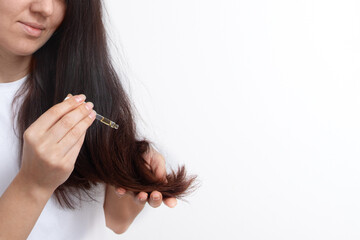 Young woman with long hair and a pipette in her hand. Hair treatment and care. Copy space
