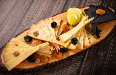 Food photography. Close up view of a plate with a large variety of cheese from different countries against a wooden table.