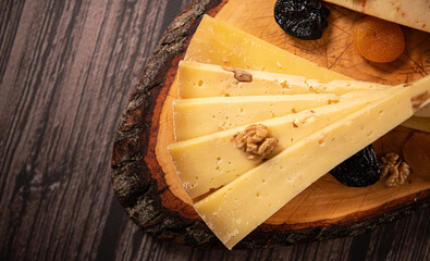 Food photography. Close up view of a plate with a large variety of cheese from different countries against a wooden table.