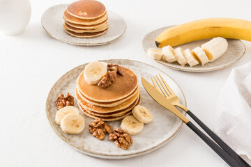 delicious homemade pancakes on a ceramic plate with banana slices and walnuts. a traditional American dessert.