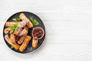 Churros with powdered sugar and chocolate sauce. Fast food sweets