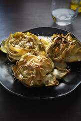 Baked artichoke flowers in dark plant and with dark wood background