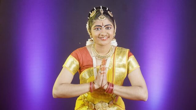 Indian bharatanatyam dancer greeting by doing namaste while looking at camera on stage - concept of traditional confident artist, classical dance performance and hobbyist.