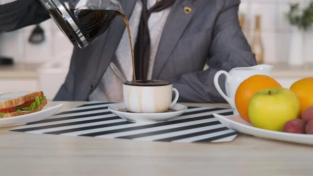 Closeup of Hand of Businessman Pouring Coffee at Home. Coffee Spills over the Rim of Cup. Loopable Cinemagraph Video, Motion Photo