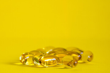 Fish oil capsule, yellow omega 3 capsules, yellow oil tablets on a yellow background
