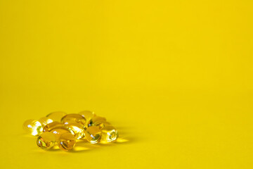 Fish oil capsule, yellow omega 3 capsules, yellow oil tablets on a yellow background