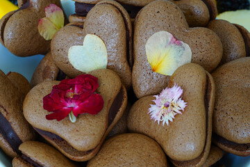 Fototapeta na wymiar Heart shaped chocolate macaron cookies with pressed edible flowers for Valentines Day