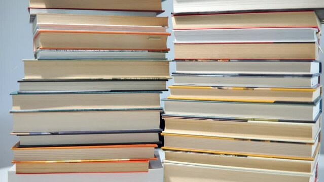 Heap of books stacked reciprocally on a table - tilt down shot