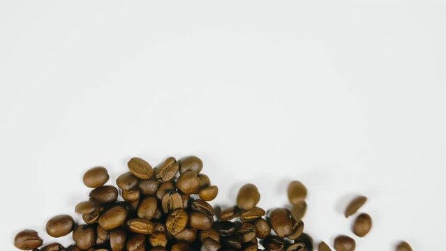 The coffee beans spin rotate quickly fast fly, dispart, splash to the sides with centrifugal coriolis force. The video is in reverse. Twist, create pattern, make design picture. Pressurized air wind.