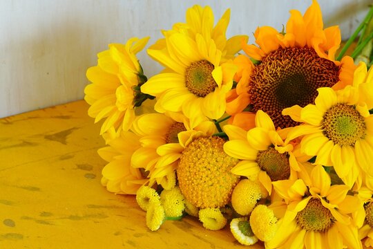 A bouquet of yellow flowers with craspedia, daisies and sunflowers