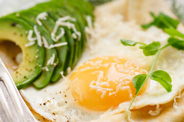 Fried eggs with slices of fresh avocado and cheese