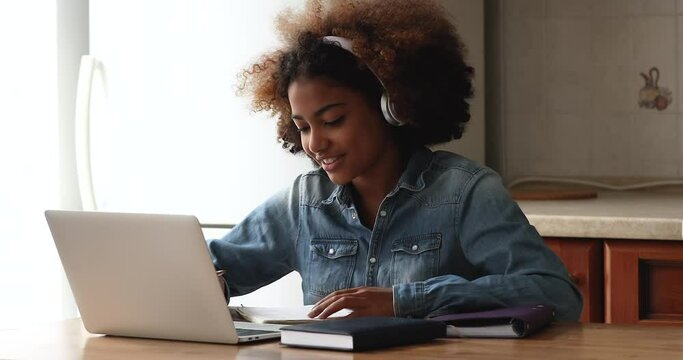 African teenage girl sit at table discuss exercise do collaborative task with high school schoolmate remotely, talk on videoconference app use laptop. E-study, gen Z, videocall event, tuition concept