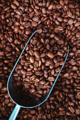 Freshly roasted coffee beans macro view from the top. Coffee on a metal spoon close-up. Stylish poster for your design and business. Beautiful coffee concept for confectionery, bakery and coffee shop.