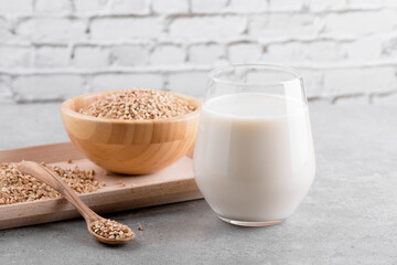 Vegan non diary buckwheat milk in glass with wooden bowl with buckwheat groats on a grey stone table. Vegan buckwheat drink is plant based alternative milk . Veggies healthy milk product, close up