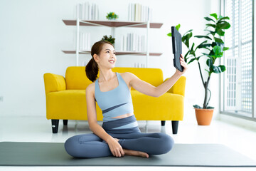 Fototapeta na wymiar asian Thailand woman exercising doing yoga at home smiling happily Have a strong body good health beautiful skin. using a tablet