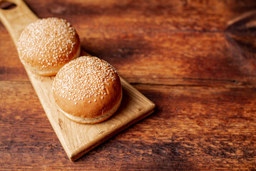 Hamburger buns. Sesame seeds on top. Wooden background. Food concept. Place for text.