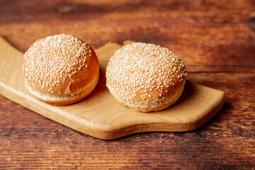 Two hamburger buns. Sesame seeds on top. Wooden background. Food concept.