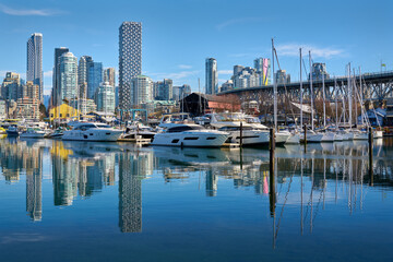 Vancouver, British Columbia, Canada – February 13, 2022. Granville Island Marina Blue Sky Reflections. Yachts in Granville Island Marina on a sunny afternoon. Vancouver, British Columbia, Canada.

