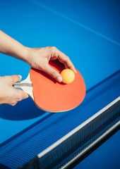 A woman's hand holding a table tennis racket next to the net