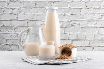Vegan non diary buckwheat milk in bottle, in jug and glass with buckwheat groats in a bowl and on white table, close up