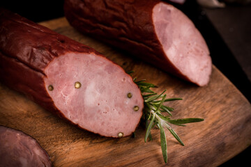 Smoked, dry krakowska, zywiecka sausage on a wooden cutting board. Polish cold cuts, meat products.