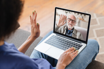 Fototapeta na wymiar Daughter granddaughter talking with her senior old elderly grandfather on laptop having video call conversation conference online. Back view. Family on lockdown distance.
