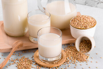 Vegan non diary buckwheat milk in glasses with buckwheat groats in a bowl on white stone table. Vegan buckwheat drink is plant based alternative milk . Veggies healthy milk product, selective focus