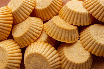Tartlets made of dough lie on a wooden board.