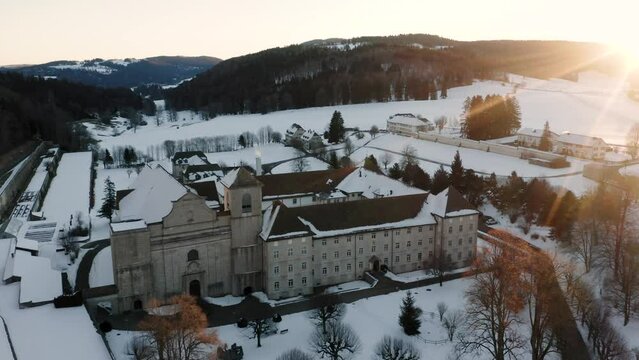 The abbey of Bellelay, historical monument of the Bernese Jura in Switzerland, drone view during a cold winter and snowy sunrise