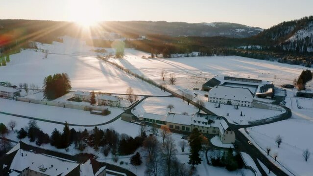 Beautiful aerial view by drone, of a small Swiss village (Bellelay) during a cold winter and snowy sunrise