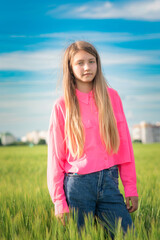 Portrait of a beautiful young girl in a summer field outside the city.